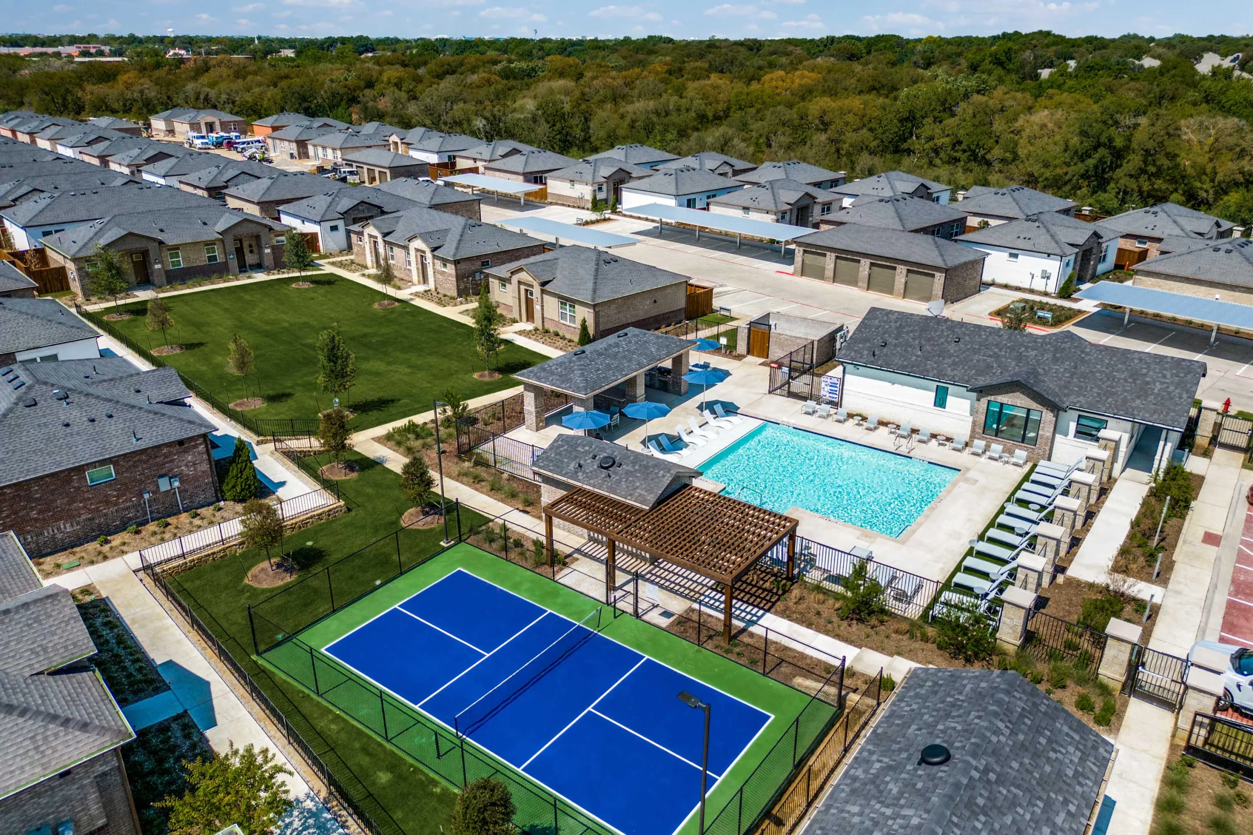 Aerial view of pickleball court, pool, grass area, and welcome center